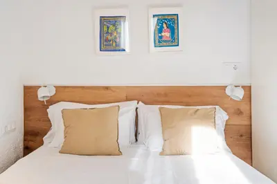 a white bed with two pillows and two pictures on the wall at Flateli Borrell in Barcelona