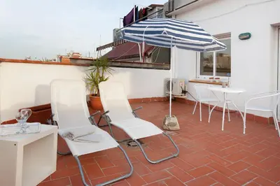 a patio with white chairs and an umbrella at Flateli Roger 16 in Barcelona