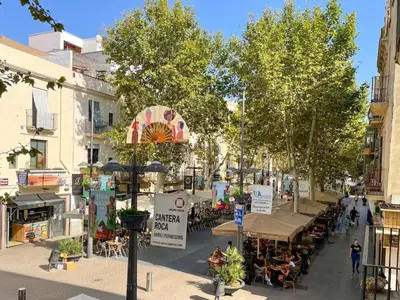 a street with trees and people sitting at tables at Apartment Rafol in Vilanova i la Geltrú
