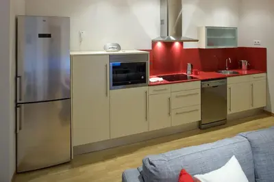 a kitchen with a stainless steel refrigerator and red cabinets at Flateli Pelayo H1 in Barcelona