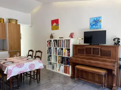 a dining room with a table and a piano at Bright airy family style 7 min walk to beach in Caldes d'Estrac