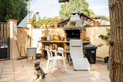 a dog sitting on a patio with chairs and an oven at Casa de Invitados in La Floresta Pearson