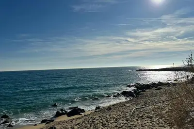 a beach with rocks and the ocean on a sunny day at La Casita de Caldetes in Caldes d'Estrac