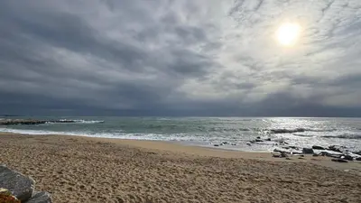 a beach with a cloudy sky and the ocean at La Casita de Caldetes in Caldes d'Estrac