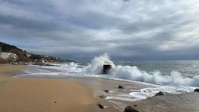 a wave breaking on a beach with the ocean at La Casita de Caldetes in Caldes d'Estrac