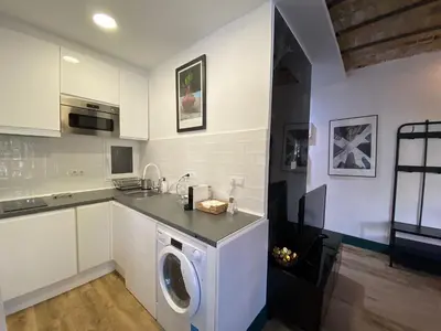 a kitchen with a washing machine in a white kitchen at Barcelona Rent - Gaudi House in Barcelona
