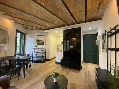 a living room with a table and a green door at Barcelona Rent - Gaudi House in Barcelona