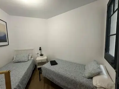 a bedroom with two beds and a nightstand and a window at Barcelona rent - Picasso House in Barcelona