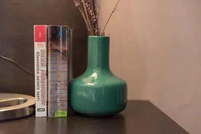 a green vase sitting on a table next to a book at Plaza Catalunya City Center Apartments in Barcelona
