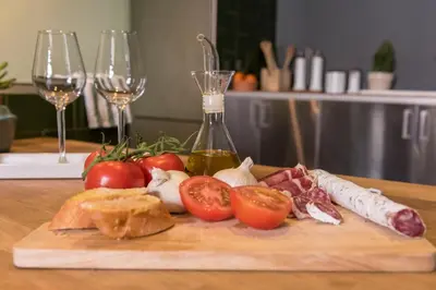 a cutting board with vegetables on a table with wine glasses at Plaza Catalunya City Center Apartments in Barcelona