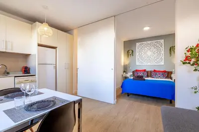 a kitchen and a bedroom with a blue bed in a room at Modern Apartment 2 rooms 15' Bcn Center - Fira Barcelona in Barcelona
