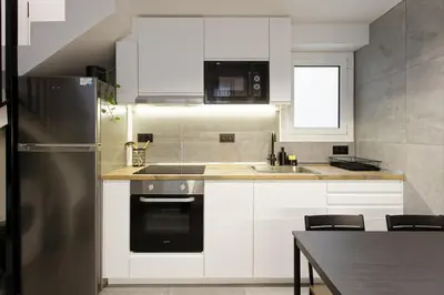 a kitchen with white cabinets and a stainless steel refrigerator at Mediterranean Bliss in Sant Adria de Besos