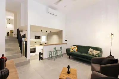 a living room with a green couch and a kitchen at Mediterranean Bliss in Sant Adria de Besos