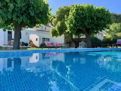 a blue swimming pool with trees and pink chairs at Bed & Breakfast Wine & Cooking Penedès in Pla del Panadés