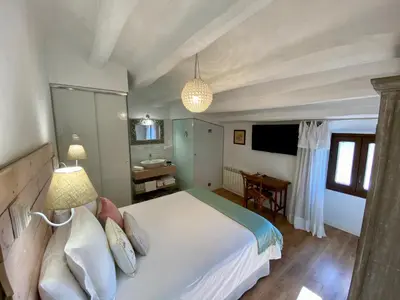 a bedroom with a large white bed and a bathroom at Bed & Breakfast Wine & Cooking Penedès in Pla del Panadés