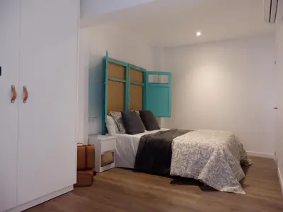 a bed with a black and white comforter and a window at Loft reformado in Cornellà de Llobregat