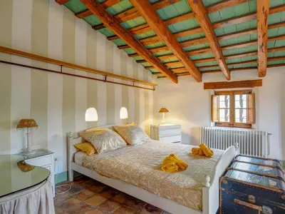 a bedroom with a bed and a wooden ceiling at Masia Palou Alt by Hello Homes Sitges in Sitges