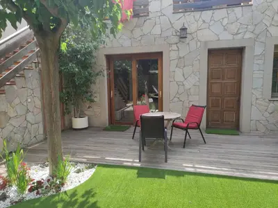a wooden deck with chairs and a table in a yard at Alojamiento independiente de invitados el Olivo in El Prat de Llobregat