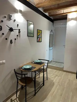 a dining room with a table and chairs and a clock at Stay Happy in Barcelona