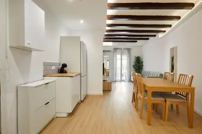 a kitchen and dining room with white cabinets and a wooden table at 17 Nice apartment next to El Molino in Barcelona