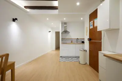 a kitchen with white cabinets and a wooden floor at 17 Nice apartment next to El Molino in Barcelona