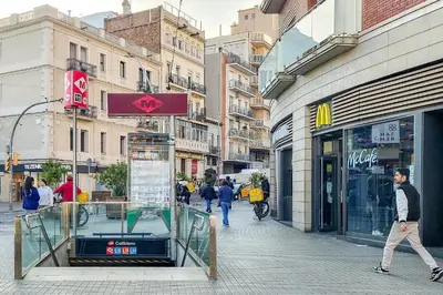 a man walking down a street next to a store at StayCampNou 1BR with Balcony in Hospitalet de Llobregat