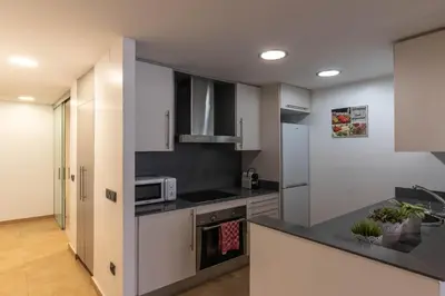 a kitchen with white cabinets and a stove top oven at Acogedor apartamento Diagonal Mar in Barcelona
