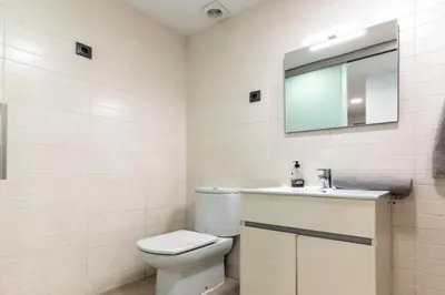 a bathroom with a toilet and a sink and a mirror at Acogedor apartamento Diagonal Mar in Barcelona