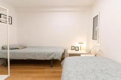 a white room with two beds and a mirror at Lindo apartamento Montjuïc in Barcelona