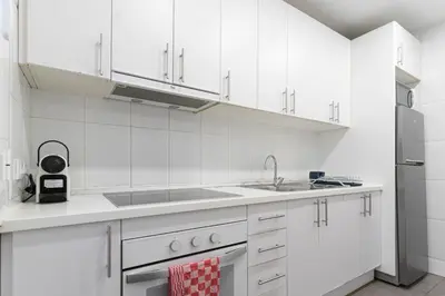 a white kitchen with a sink and a refrigerator at Lindo apartamento Montjuïc in Barcelona