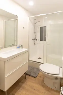 a white bathroom with a toilet and a shower at Lindo apartamento Montjuïc in Barcelona