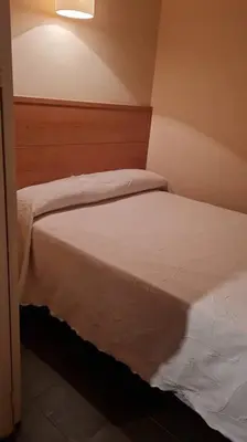 a small bedroom with a bed with white sheets at EL born - spacious 2 bedrooms in Barcelona
