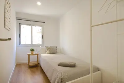 a small white room with a bed and a window at Charming and quiet apartments near Barcelona in Hospitalet de Llobregat