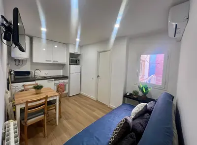 a living room with a blue couch and a kitchen at Charming and quiet apartments near Barcelona in Hospitalet de Llobregat