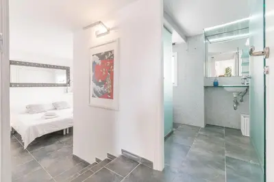 a room with a bed and a bathroom with a sink at Esencia Mediterránea Precioso en primera linea in Sitges