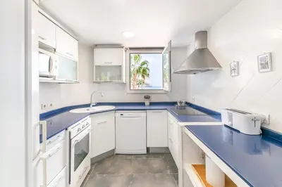 a kitchen with white cabinets and blue countertops at Esencia Mediterránea Precioso en primera linea in Sitges