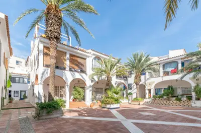a courtyard with palm trees in front of a building at Esencia Mediterránea Precioso en primera linea in Sitges