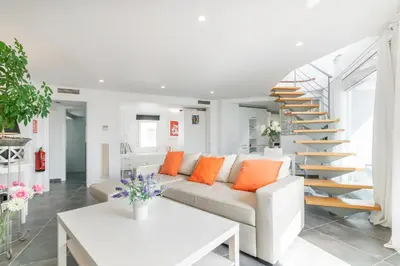 a white living room with a couch and a staircase at Esencia Mediterránea Precioso en primera linea in Sitges