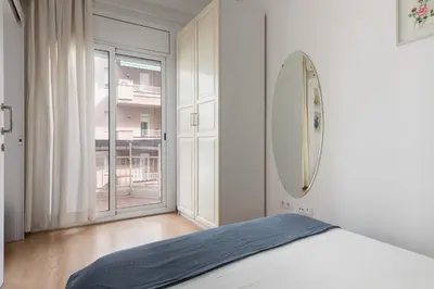 a white bedroom with a bed and a large window at Lets Holidays Centric Apartment in Barcelona in Barcelona
