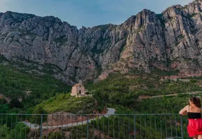 a woman standing on a fence looking at a mountain at Casa Annie in Collbató