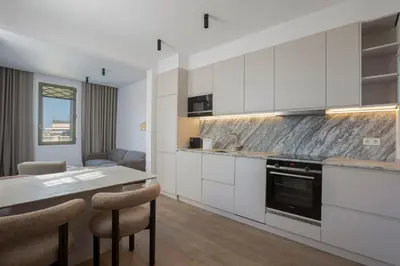 a kitchen with white cabinets and a table with chairs at The Diagonal Suites Atic by Sweett in Barcelona