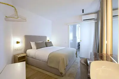 a white bedroom with a bed and a glass table at The Diagonal Suites Atic by Sweett in Barcelona