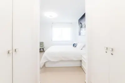 a white bedroom with a bed and a window at Frente a mar salida directa playa solo 30M agua in Cubelles