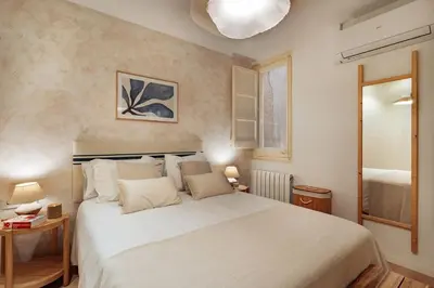 a bedroom with a large white bed and a mirror at Casa Calders in Barcelona