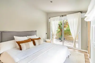 a white bedroom with a large bed and a window at Villa Atardecer in Barcelona