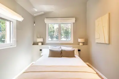 a bedroom with a large bed with two windows at Villa Atardecer in Barcelona