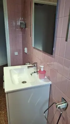 a bathroom with a sink and a mirror and pink tiles at La Garsa in Aiguafreda