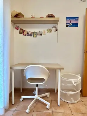 a desk with a white chair and a table and shelves at Apartamento Sant Josep in Canet de Mar
