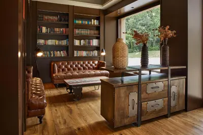 a living room with a leather couch and a book shelf at Mas Salagros EcoResort & SPA in Vallromanas
