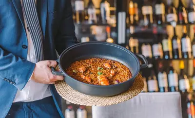 a person holding a pot of food with bottles of wine at Mas Salagros EcoResort & SPA in Vallromanas